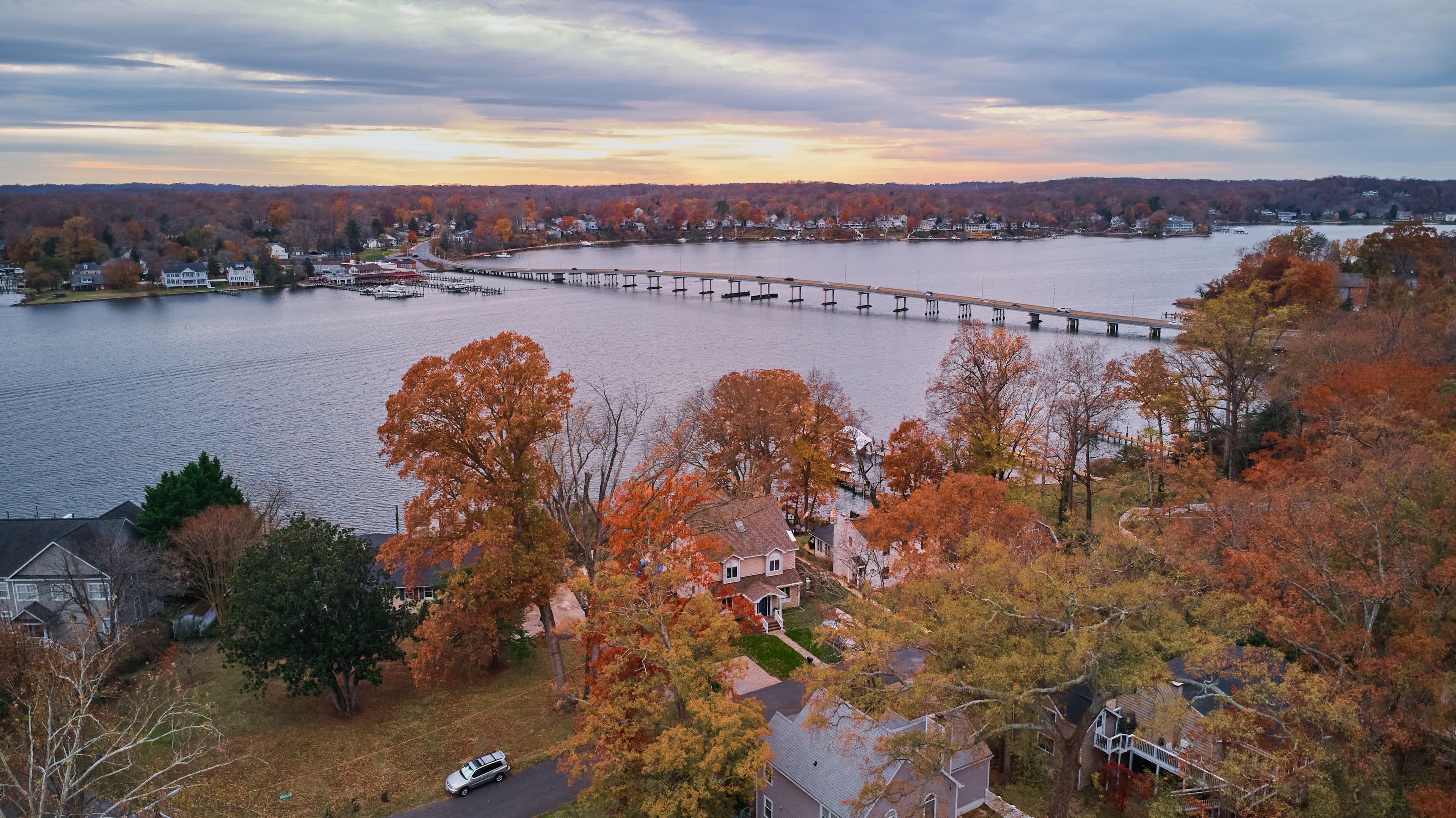 Aerial view of the South River Bridge and waterfront homes in fall foliage at sunset